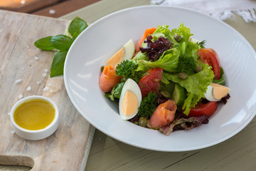 Vegetable salad with egg and salmon served with basil and topping sauce