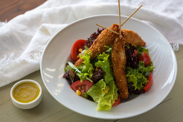 Fried chicken on wooden skewers with vegetable salad and sauce. Spring picnic,,. Delicious lunch. On light background