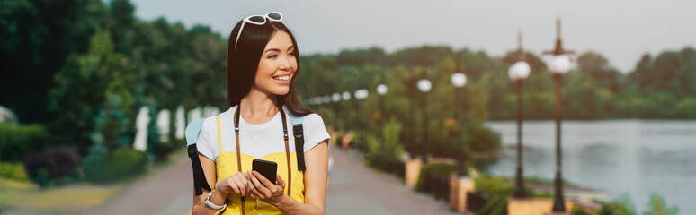 panoramic shot of asian and attractive woman holding smartphone