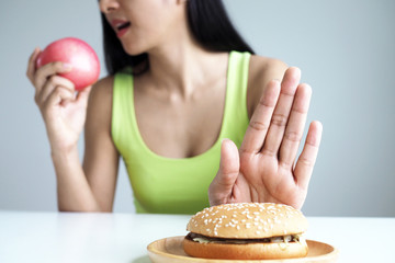 Asian women push the hamburger plate and choose to eat apples for good health.