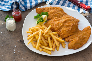 Chicken schnitzel. Breaded chicken schnitzel fries potatoes and sauces
