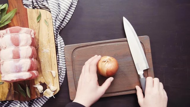 Flat lay. Dicing onion and garlic to season boneless pork roast.