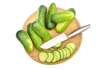 Cutted and whole cucumbers with knife on cutting board. Top view.