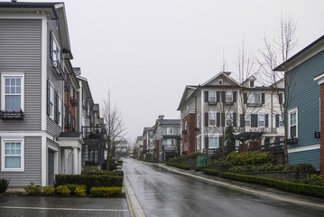 Road with new residential townhouses on cloudy rainy day