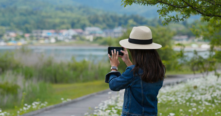 Obraz premium Woman takes photo with cellphone in countryside