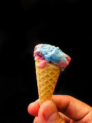 Man hand holding ice cream cone isolated on black colored background