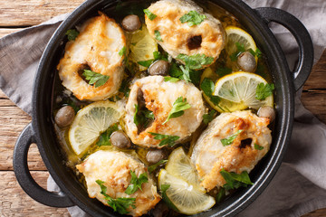 Spicy cod steaks baked with lemon and olives closeup in a pan. horizontal top view