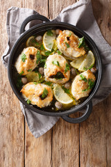 Greek cuisine cod steaks with lemon and olives closeup in a pan. Vertical top view