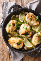 Baked cod steaks with lemon and olives closeup in a pan. Vertical top view