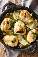 Spicy cod steaks baked with lemon and olives closeup in a pan. Vertical top view