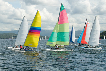 Children Sailing small sailboats with colourful sails on an inland waterway.