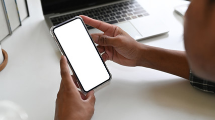 Man using mockup mobile phone on office desk with clipping path display.