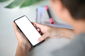 Cropped shot hands using mockup smartphone on office desk with clipping path.