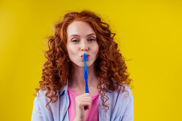 woman redhaired ginger with eco toothbrush and toothpaste on yellow studio background