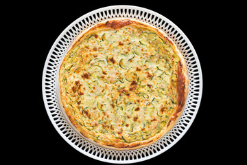 Homemade savory cake with zucchini isolated on black background.  Cake with eggs, sour cream, milk, salt, pepper, puff pastry, sauteed zucchini, emmental cheese  