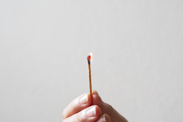 Hand holding burning match stick.