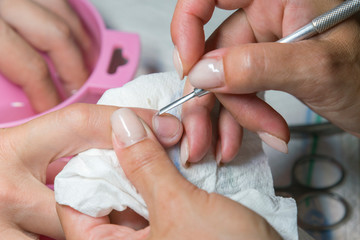 Obraz na płótnie Canvas Woman hands receiving manicure and nail care procedure. Close up concept. Manicurist pushing cuticles on female's nails. female nail manicure processing