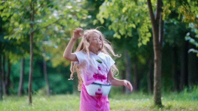 Cute little girl in the park. Carefree little girl dancing on grass and having fun in park
