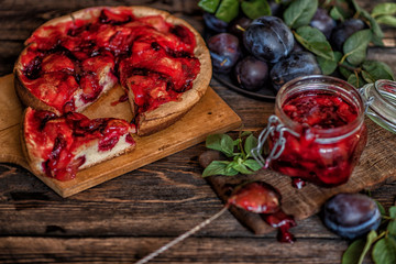 Homemade plum pie and jam in a glass jar, autumn dessert with fresh plums, baking, healthy vegetarian food.