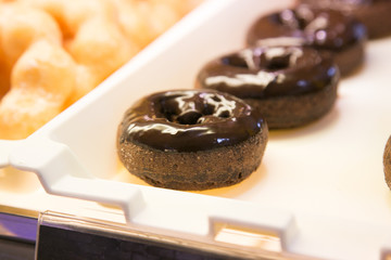 Ring doughnut fresh from the bakery with sprinkle sweets and icing on top.