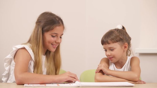 Little sisters are looking at pictures and discussing what they see. Professional therapist using picture interpretation technique