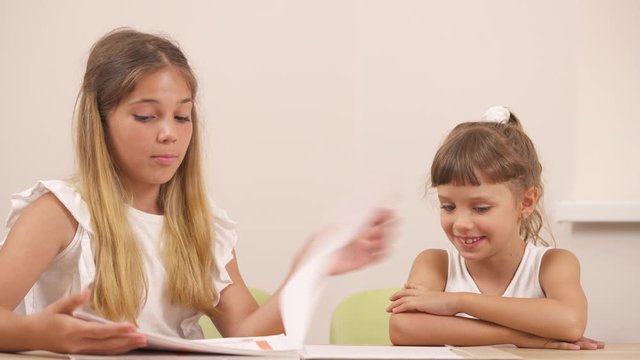 Close-up demonstration video of two adorable girls looking at pictures and discussing what they see during psychological session.