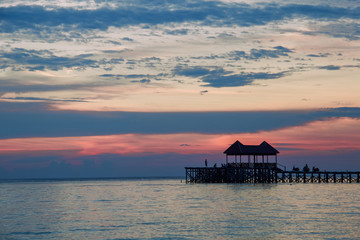 Fototapeta premium silhouettes of wooden pier and people at tropical sunset
