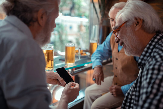 Man showing smartphone while drinking beer with friends