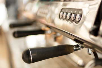 close up view of portafilters handles in a row of professional coffee machine on kitchen. buttons, sunny day, vintage color tones