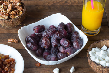 Delicious dietary breakfast. White dish with date fruits inside, glass of freshly squeezed orange...