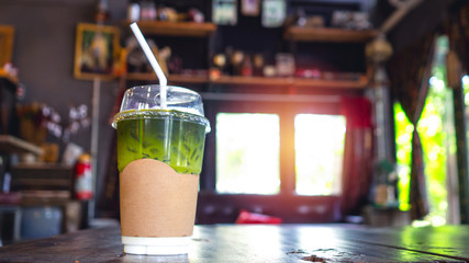Cool green tea in a glass of pasta Placed on a table in a cafe decorated with wood.
