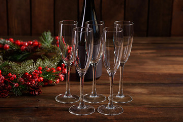 Christmas holiday table with glasses and a bottle of wine of champagne. Eve of new year, preparation and laying of a wooden holiday table