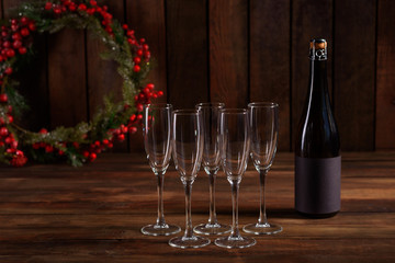 Christmas holiday table with glasses and a bottle of wine of champagne. Eve of new year, preparation and laying of a wooden holiday table