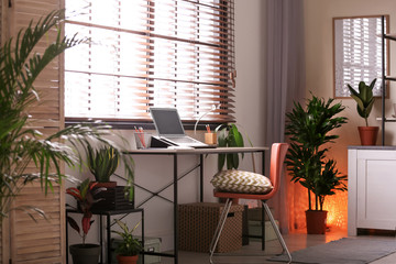Room interior with workplace and different potted houseplants