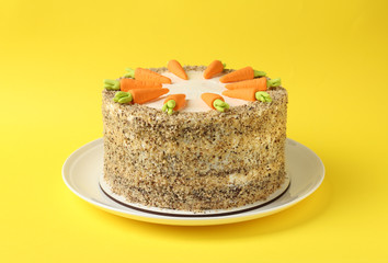 Dish with tasty carrot cake on yellow background