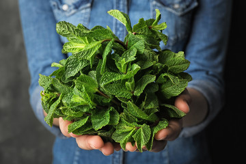 Young woman holding bunch of fresh mint, closeup © New Africa
