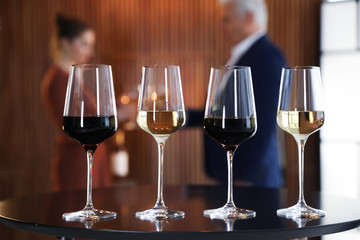 Glasses of different wines on table against blurred background