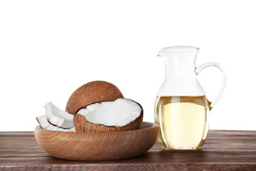 Composition with natural organic oil and ripe coconuts on wooden table against white background