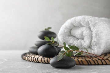 Composition with spa stones, towel and green leaves on grey table, space for text