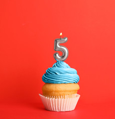 Birthday cupcake with number five candle on red background