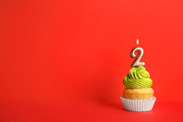 Birthday cupcake with number two candle on red background, space for text
