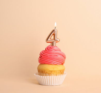 Birthday cupcake with number four candle on beige background