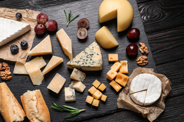 Flat lay composition with different types of delicious cheese on slate board