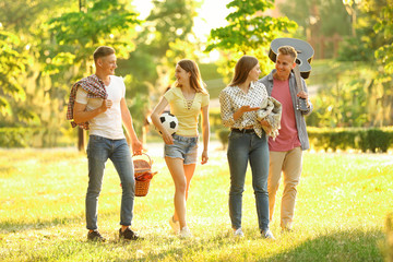 Young people with picnic basket in park on summer day