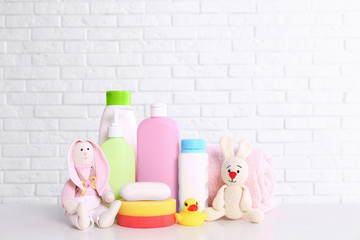 Baby accessories on table near white brick wall. Space for text