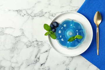 Plate of delicious blue jelly with berries on marble background, top view. Space for text