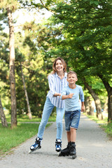 Obraz premium Mother and son roller skating in summer park