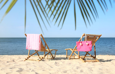 Empty wooden sunbeds and beach accessories on sandy shore