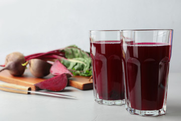 Glasses of beet juice on light table. Space for text