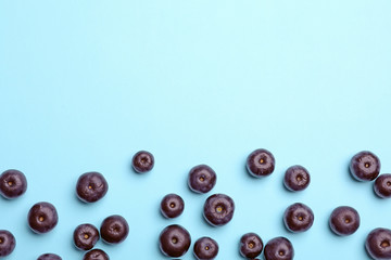 Fresh acai berries on blue background, flat lay. Space for text